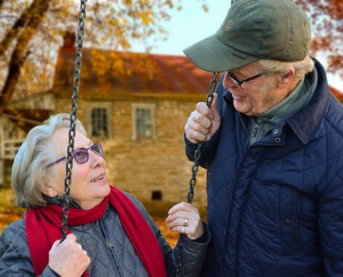 assisted living, elderly woman swinging and talking to elderly man